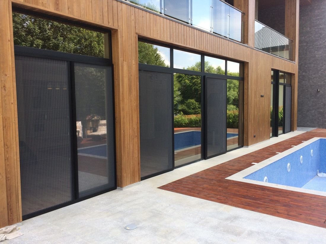 Black aluminum window and door system with safe glass railings and pleated screens for a private home in Kojori.